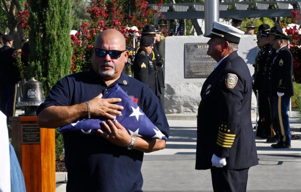 Retired Port Authority of New York and New Jersey Police Detective and World Trade Center attack survivor and guest speaker William Jimeno, left, carries an American flag presented to him Monday morning, Sept. 11, 2023 in Clovis.