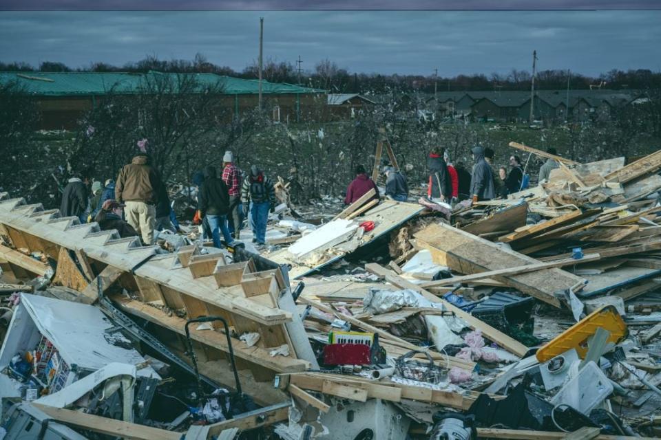 Residents and visitors work to clear debris in search of pets and belongings of a destroyed home in Clarksville, Tennessee.