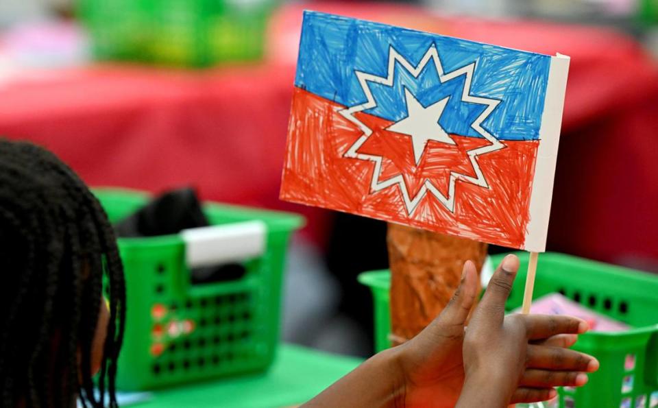 A child holds up a finished Juneteenth flag she colored on Friday at the Manatee County Central Library during the 7th annual Juneteenth Reading Conference.