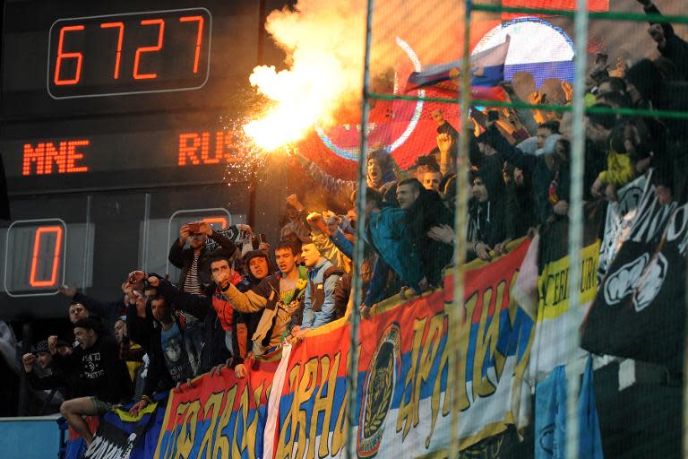 Russian supporters light a flare during the Euro 2016 qualifying football match between Montenegro and Russia in Podgorica on March 27, 2015