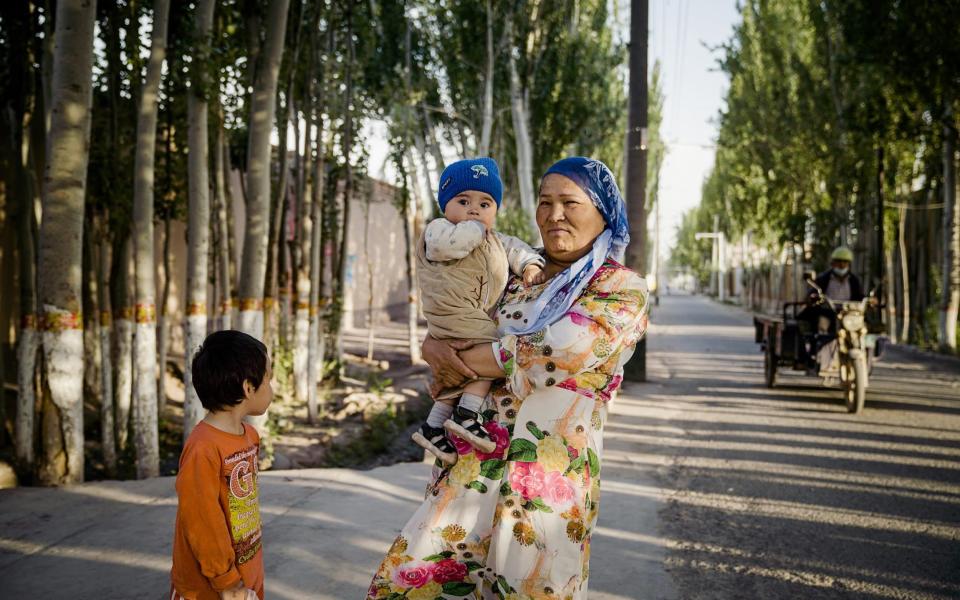 A Uyghur woman and her children stand in the outskirts of Kashgar, Xinjiang - Lorenz Huber 
