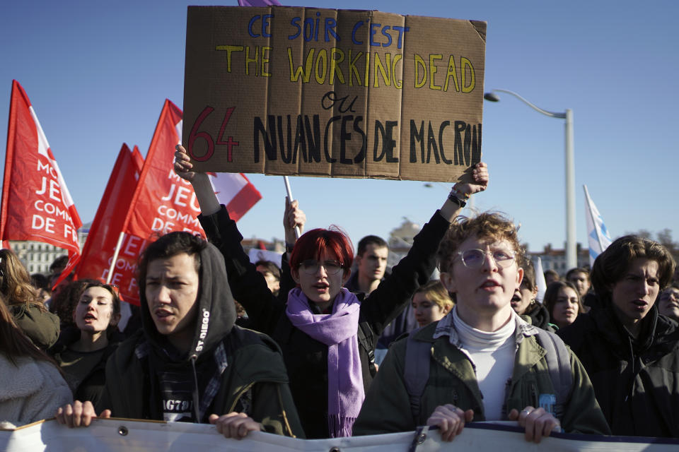 Demonstrators of universities hold a placard reading "Tonight it is The Working Dead, or 64 Shades of Macron" during a march against pension reforms in Lyon, central France, Tuesday, Feb. 7, 2023. Public transportation, schools and electricity, oil and gas supplies were disrupted on Tuesday in France as demonstrators were taking to the streets for a third round of nationwide strikes and protests against the government's pension reform plans. (AP Photo/Laurent Cipriani)