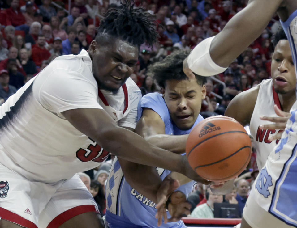 North Carolina State forward D.J. Burns Jr., left, and guard LJ Thomas, right, battle North Carolina forward Puff Johnson, center, for the ball during the second half of an NCAA college basketball game, Sunday, Feb. 19, 2023, in Raleigh, N.C. (AP Photo/Chris Seward)