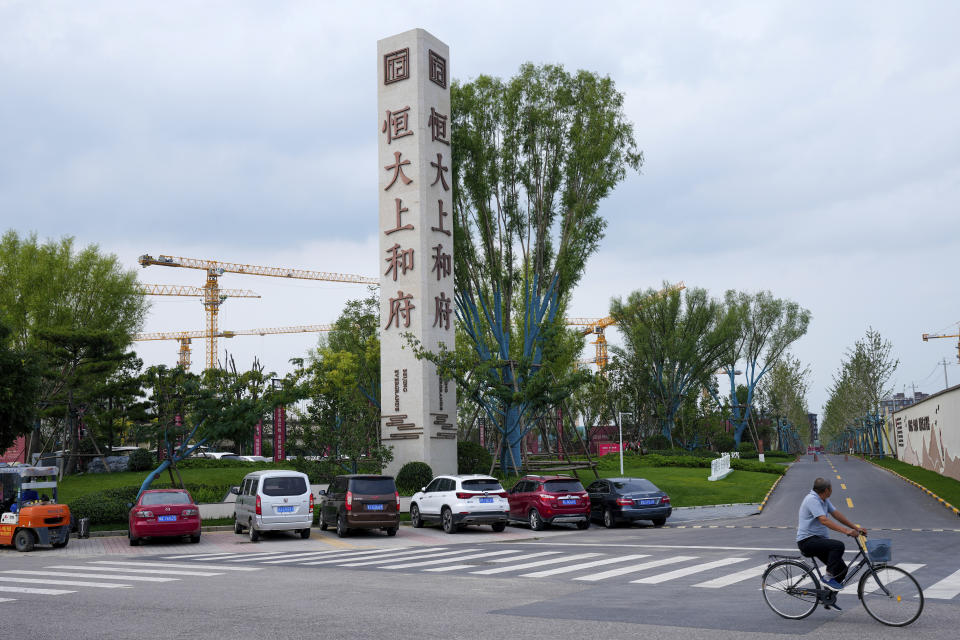 A man bicycles past an Evergrande new housing development in Beijing, Wednesday, Sept. 15, 2021. One of China's biggest real estate developers is struggling to avoid defaulting on billions of dollars of debt, prompting concern about the broader economic impact and protests by apartment buyers about delays in completing projects. Rating agencies say Evergrande Group appears likely to be unable to repay all of the 572 billion yuan ($89 billion) it owes banks and other bondholders. That might jolt financial markets, but analysts say Beijing is likely to step in to prevent wider damage. (AP Photo/Andy Wong)