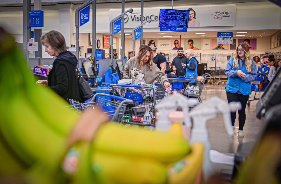 Shoppers buy groceries like dairy, vegetables and produce at self-checkout stations with the help of cashiers Joanne Moore and Taylor Brashears at a Walmart in Loveland on Oct. 13.