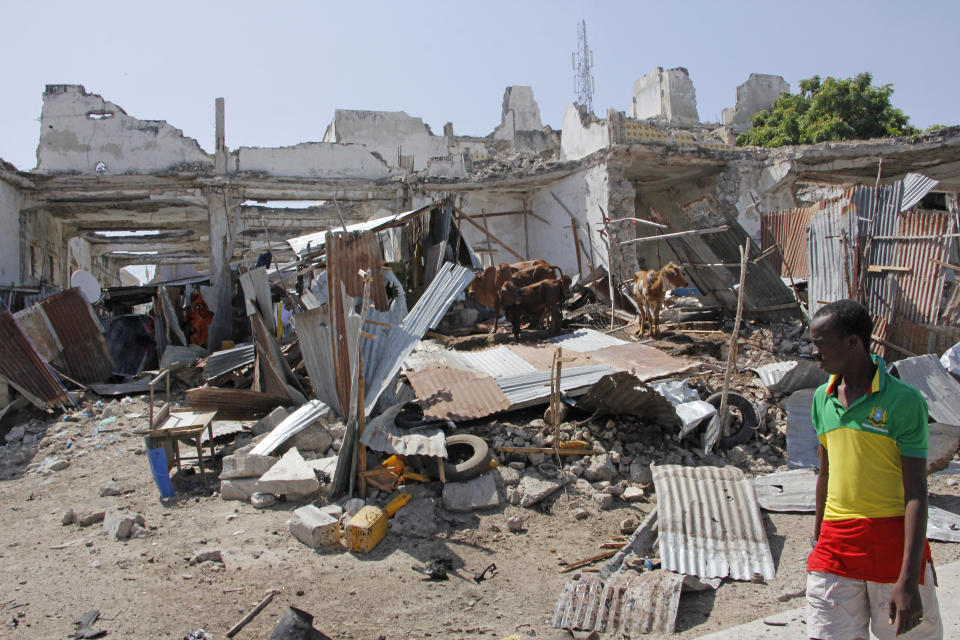 A man walks near destroyed buildings after a bomb blast in the capital city of Mogadishu, Somalia, Saturday, Dec. 22, 2018. Police say a suicide car bomb exploded near the presidential palace killing and wounding a number of people. (AP Photo/Farah Abdi Warsameh)