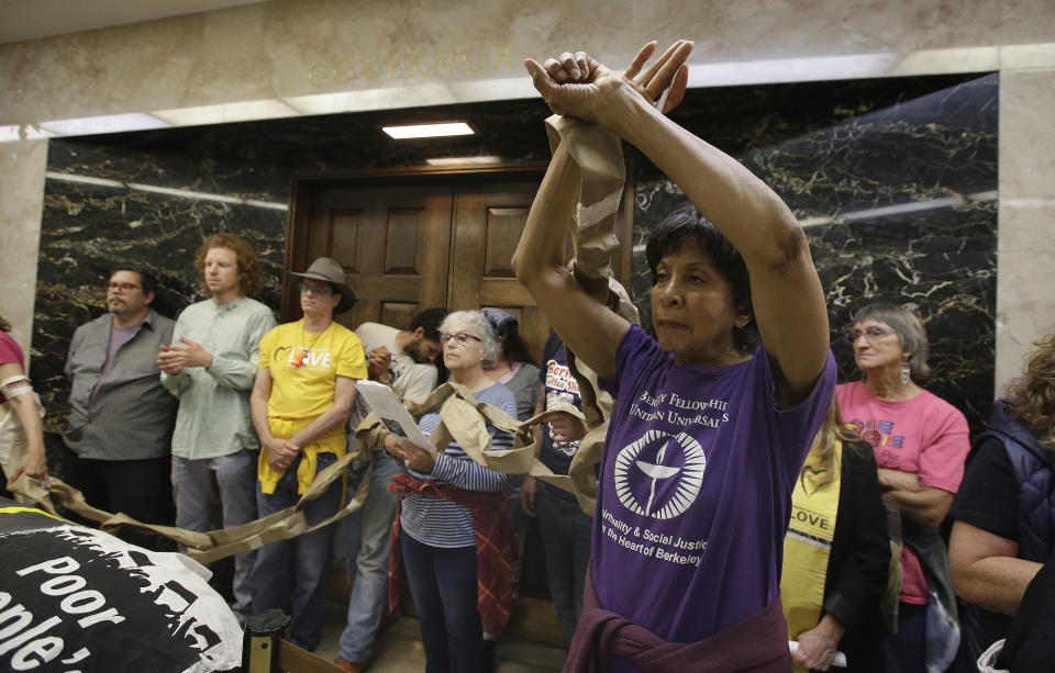 Virginia Hollins-Davidson , right, join other protesters blocking the door to the governor's office during a protest by the Poor People's Campaign at the Capitol, Monday, June 18, 2018, in Sacramento, Calif. The group has been advocating for a variety of causes, including reducing income inequality, preserving the environment and improving health care for the poor. (AP Photo/Rich Pedroncelli)