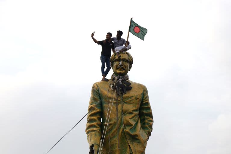 Varias personas se hacen un selfie mientras intentan destruir la estatua del padre de Sheikh Hasina, Sheikh Mujiban Rahman, instalada en Vijay Swarani, en Dhaka