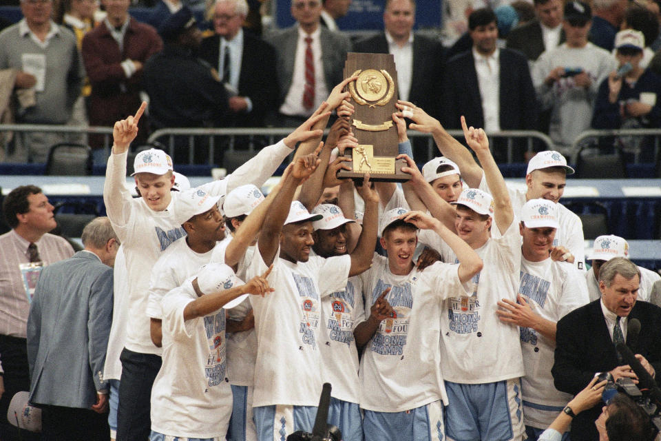 FILE - In this Monday, April 5, 1993, file photo, North Carolina poses with the trophy after defeating Michigan 77-71 in the NCAA Final Four Championship game at the Superdome in New Orleans, La. At far right is coach Dean Smith. Smith won his second national championship, and like the first title he won at the Superdome, this one wasn’t sealed until somebody made a costly, almost unbelieveable, error. (AP Photo/Bob Jordan, File)