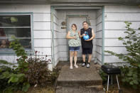 Misty Castillo, left, and her husband Arcadio stand in front of their home, holding the urn containing the ashes of their son Arcadio Castillo III, who was shot in 2021 by Salem police, as their granddaughter Nala, age 2, looks out the window in Salem, Ore., Thursday, Aug. 18, 2022. Misty called 911 and asked for the police, saying her son was mentally ill, was assaulting her and her husband and had a knife. Less than five minutes later, a police officer burst into the house and shot him. (AP Photo/Craig Mitchelldyer)