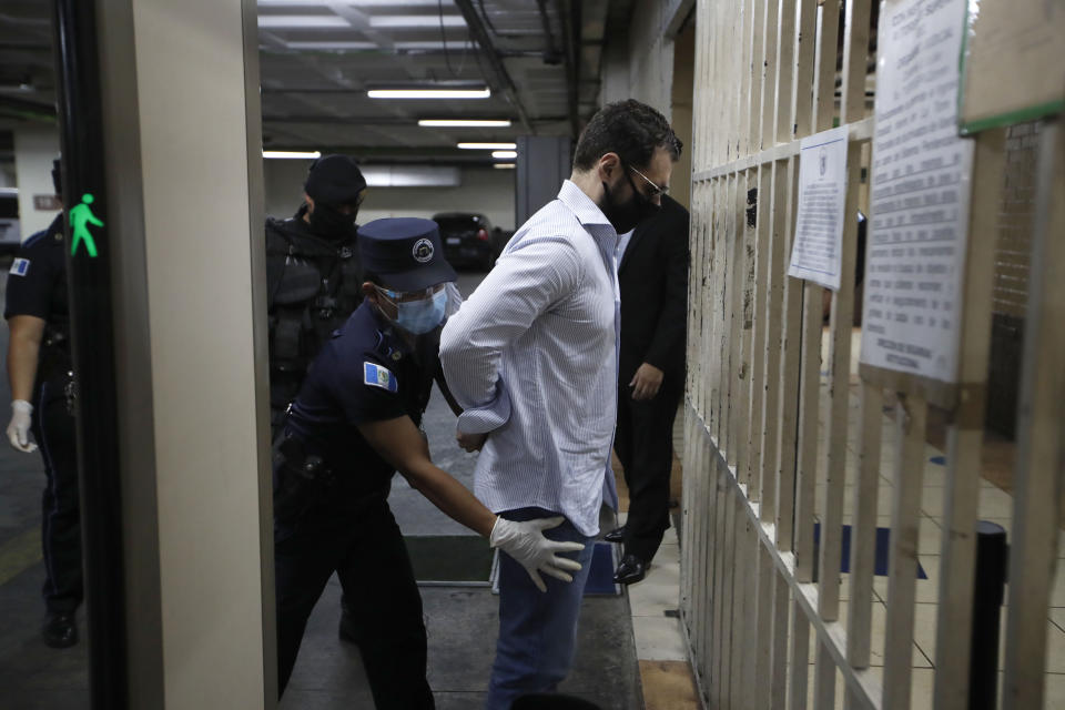 The son of former Panamanian President Ricardo Martinelli, Ricardo Martnelli Linares, is frisked by an officer before a hearing at the judicial court building in Guatemala City, Monday, July 6, 2020. Guatemalan police detained Ricardo Martnelli Linares and his brother Luis Enrique Martnelli Linares on an Interpol warrant for money laundering, as they attempted to board a private plane out of the country. (AP Photo/Moises Castillo)