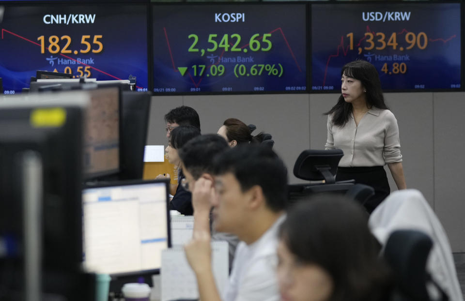 A currency trader passes by the screens showing the Korea Composite Stock Price Index (KOSPI), center, and the foreign exchange rate between U.S. dollar and South Korean won, right, at the foreign exchange dealing room of the KEB Hana Bank headquarters in Seoul, South Korea, Thursday, Sept. 21, 2023. Asian shares are lower, tracking a slump on Wall Street after the Federal Reserve said it may not cut interest rates next year by as much as it earlier thought. (AP Photo/Ahn Young-joon)