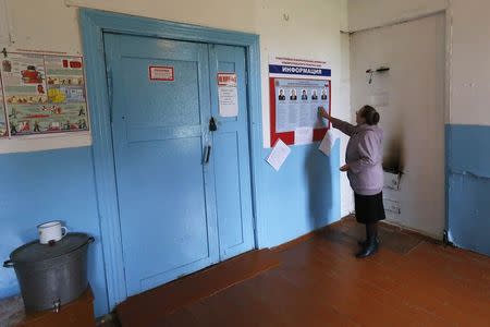 A woman looks at a list of candidates before voting in regional governors election at a polling station in the village of Verkhnaya Biryusa, south of Russia's Siberian city of Krasnoyarsk, September 14, 2014. REUTERS/Ilya Naymushin