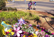 Pedestrians walk past flowers outside the complex where the Dickason family lived prior to their emigration to New Zealand, in Pretoria, South Africa, Thursday, Sept. 23, 2021. People in the town of Timaru are planning an evening vigil outside the home of three young girls who were killed last week in a crime that shocked New Zealand. The girls' mother Lauren Dickason has been charged with their murder. (AP Photo/Themba Hadebe)