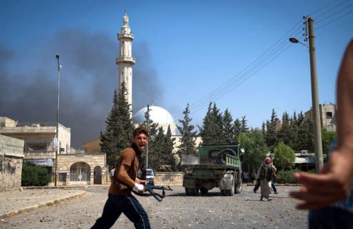 A rebel with the Free Syrian Army reacts to the sound of an aircraft following an airstrike on a building in the Hanano district of the northern restive city of Aleppo