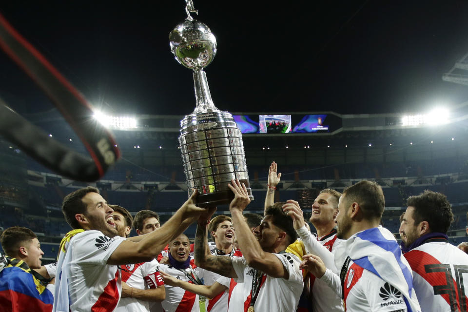 Payers of Argentina's River Plate celebrate with the trophy after defeating 3-1 Argentina's Boca Juniors in the Copa Libertadores final soccer match at the Santiago Bernabeu stadium in Madrid, Spain, Sunday, Dec. 9, 2018. (AP Photo/Manu Fernandez)