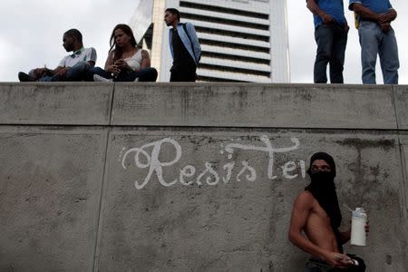 An opposition supporter paints the word "resistance" on a wall while rallying against Venezuela's President Nicolas Maduro's government in Caracas, Venezuela August 4, 2017. REUTERS/Marco Bello