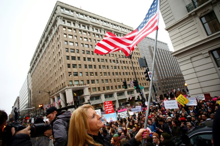 A President Donald Trump supporter waves an American flag as she is taunted by demonstrators during the Women's March in Washington, DC