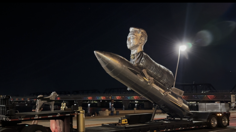 A silver sculpture of Elon Musk's head on a goat's body riding a rocket is shown.