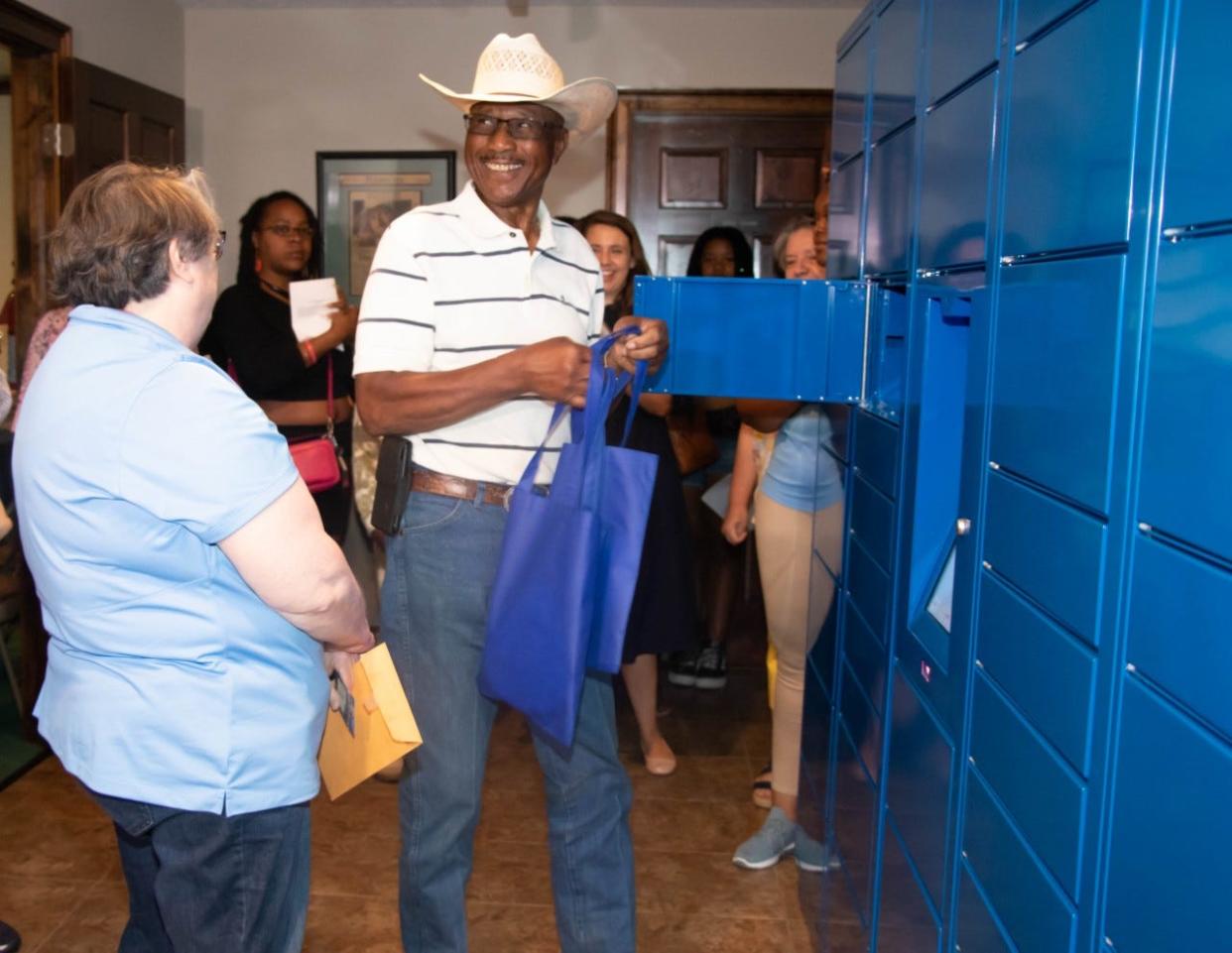 Godwin Mayor Willie J. Burnette becomes the first customer on June 28, 2022, to open a locker on the automated book locker installed in the Godwin Town Hall, after how-to instructions from Cumberland County Library Division Manager Nora Armstrong, left.