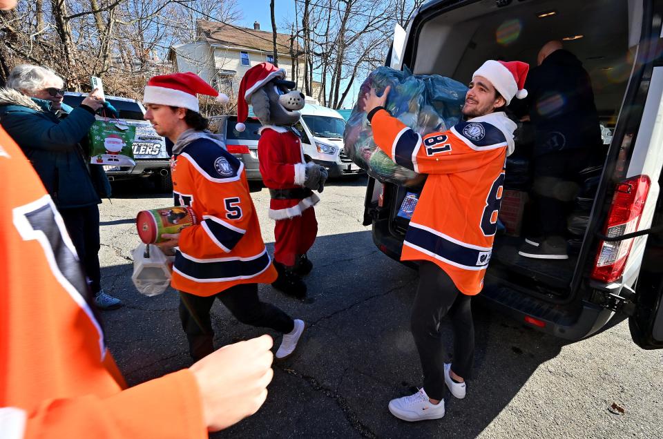 Railers players Anthony Repaci, right, and Zach White help drop off toys and teddy bears collected for Friendly House of Worcester from Saturday's game at the DCU Center.