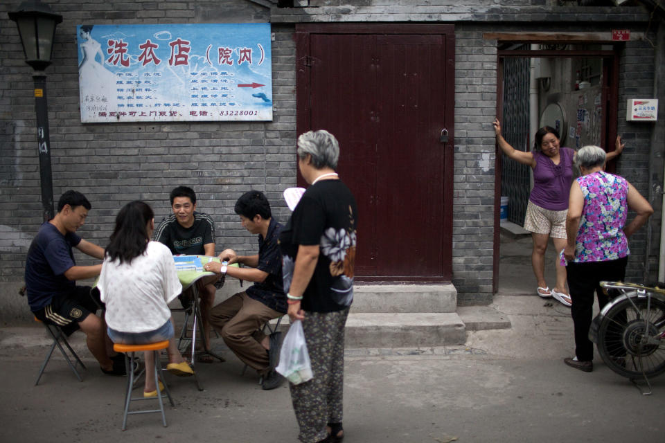 In this Sunday, July 8, 2012 photo, residents chat and play majhong after dinner time in a hutong, an old alleyway, near the Houhai lake in Beijing, China. To see a side of Beijing other than glitzy shopping malls or imposing, Soviet-style government buildings, take an afternoon to explore the city's ancient narrow alleyways, known as hutongs. (AP Photo/Alexander F. Yuan)