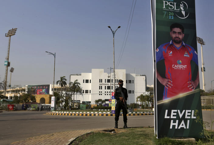 A police commando stands guard beside a poster of Pakistani cricketer Babar Azam at outside the National Stadium, where preparations under way for the upcoming country's premier domestic Twenty20 tournament 'Pakistan Super League' in Karachi, Pakistan, Tuesday, Jan. 25, 2022. The Pakistan Cricket Board says "robust" COVID-19 health and safety protocols are in place ahead of its month-long domestic Twenty20 competition in Karachi and Lahore, with several foreign cricketers participating in a six-team event. (AP Photo/Fareed Khan)
