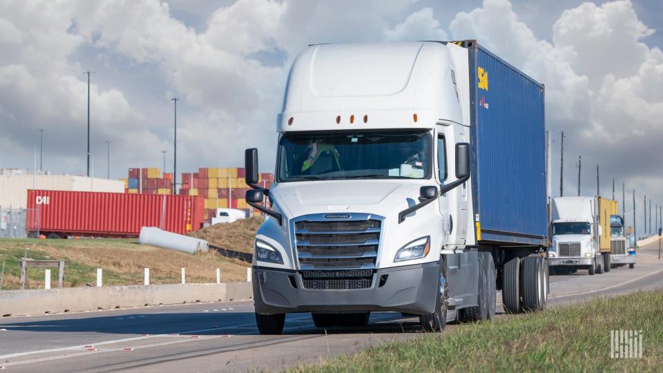 white tractor leaving the Port of Houston with a blue ocean container