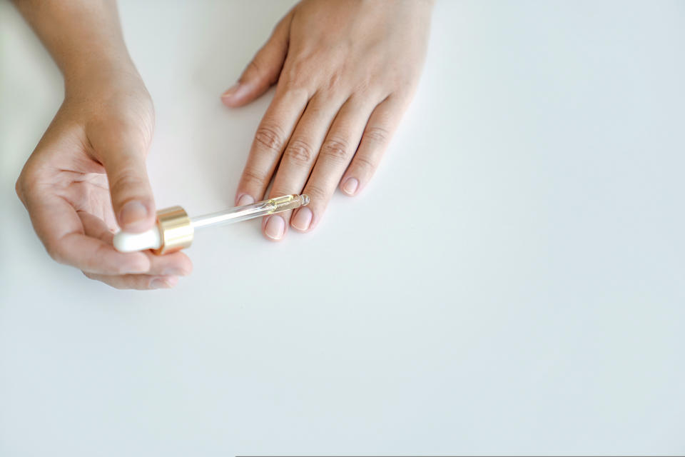 Woman applying cuticle oil onto clean, unpolished nails