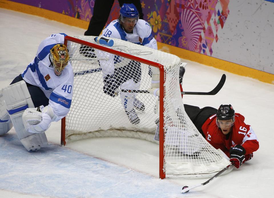 Canada's Jonathan Toews (R) tries for a wrap around on Finland's goalie Tuukka Rask (40) as Finland's Sami Lepisto (18) looks on, during the first period of their men's preliminary round ice hockey game at the Sochi 2014 Winter Olympic Games February 16, 2014. REUTERS/Brian Snyder (RUSSIA - Tags: SPORT ICE HOCKEY OLYMPICS)