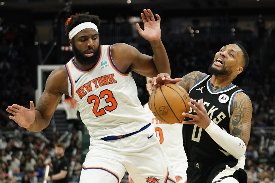 Milwaukee Bucks' Damian Lillard (0) is fouled as he drives to the basket against New York Knicks' Mitchell Robinson (23) during the second half of an NBA basketball game Sunday, April 7, 2024, in Milwaukee. (AP Photo/Aaron Gash)