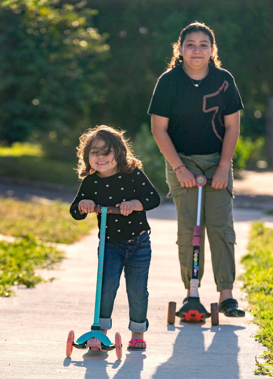 Amy Galeano, 4, rides scooters with her sister Alondra, 9, outside their home in Lake Worth Beach.