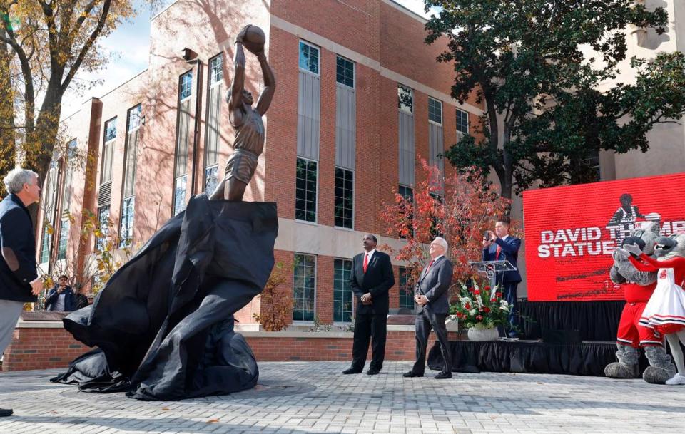 David Thompson watches as his statue is unveiled outside Reynolds Coliseum in Raleigh, N.C., Wednesday, Dec. 6, 2023. Also watching is N.C. State athletics director Boo Corrigan, left, and Chancellor Randy Woodson.