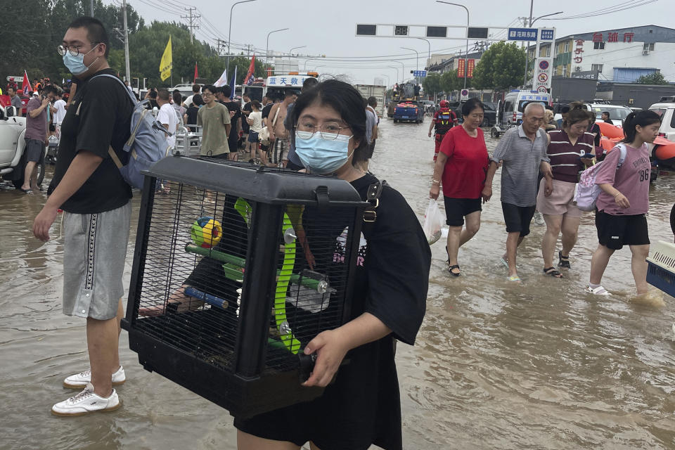 A woman evacuated from floods carries her pet bird in a cage in Zhuozhou in northern China's Hebei province, south of Beijing, Wednesday, Aug. 2, 2023. China's capital has recorded its heaviest rainfall in at least 140 years over the past few days. Among the hardest hit areas is Zhuozhou, a small city that borders Beijing's southwest. (AP Photo/Andy Wong)