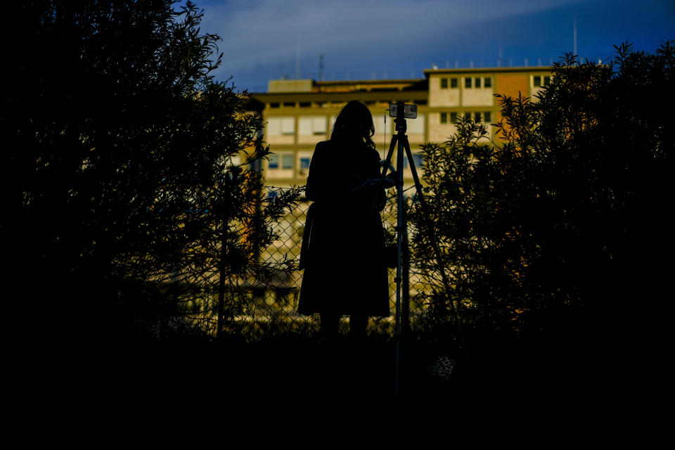 A journalists prepares for a stand up outside the Agostino Gemelli hospital in front the rooms on the top floor normally used when a pope is hospitalized, in Rome, Thursday, March 30, 2023, after The Vatican said Pope Francis has been taken there in the afternoon for some scheduled tests. The Vatican provided no details, including how long the 86-year-old pope would remain at Gemelli University Hospital, where he underwent surgery in 2021. (AP Photo/Andrew Medichini)