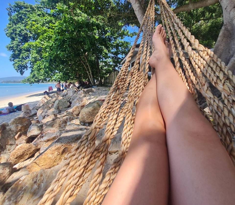 a person's feet on a rock by a beach