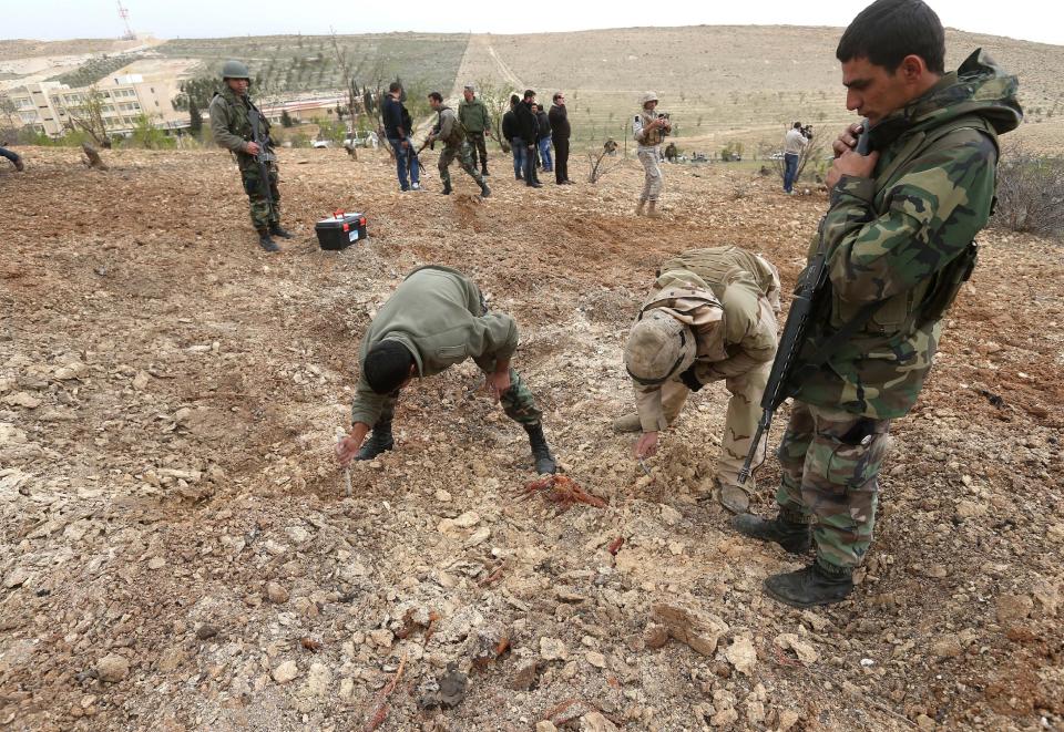 Lebanese army soldiers inspect a crater after they blew up a bomb-packed parked car in a field outside the village of Fakiha, near the Lebanese and Syria border, in northeast Lebanon, Monday, March 17, 2014. Lebanese commandos combed the tense border areas between Lebanon and Syria early Monday shortly after troops discovered and denoted an SUV rigged with explosives. The Lebanese army is searching for rebels crossing into the country after their last stronghold on the other side of the frontier fell into Syrian government hands on Sunday. (AP Photo/Hussein Malla)