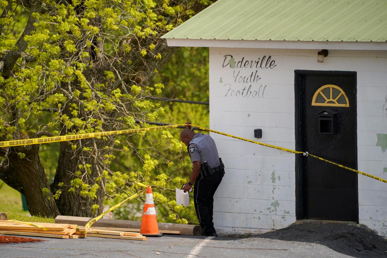A law enforcement officer goes under a piece of crime scene tape (REUTERS)