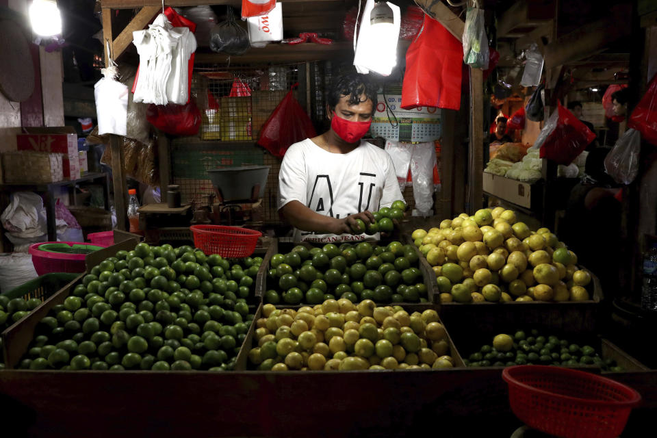 A fruit vendor wears a face mask as a precaution against the new coronavirus at his stall in a traditional market in Jakarta, Indonesia, Tuesday, June 2, 2020. (AP Photo/Tatan Syuflana)