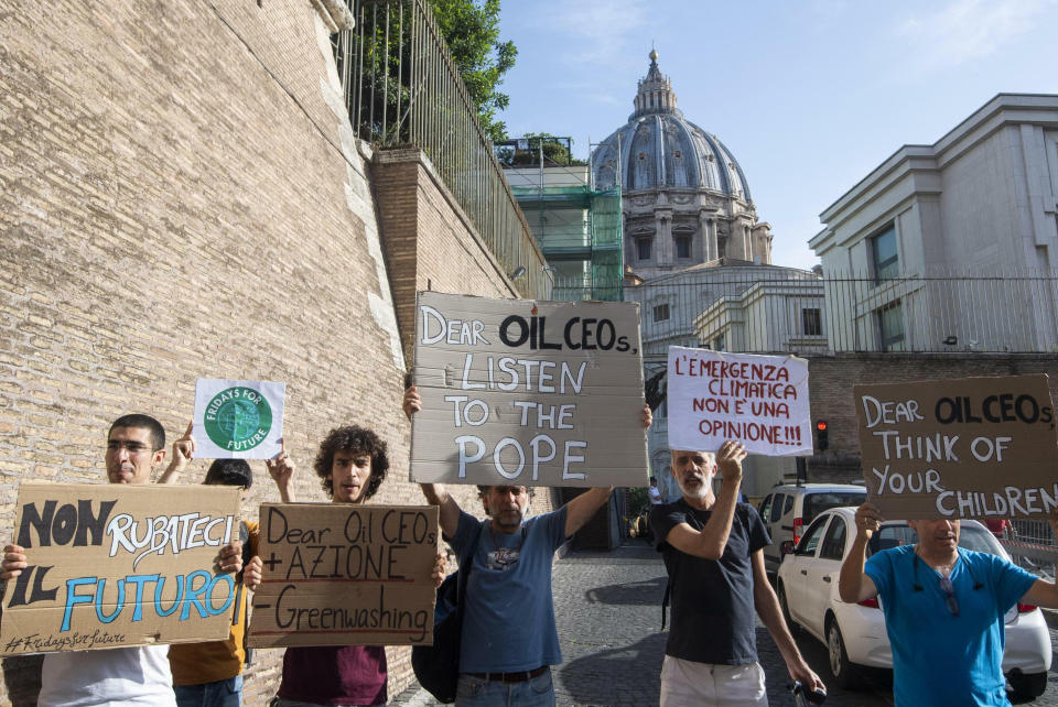 Activists hold up signs outside the Vatican as Pope Francis meets with oil executives, Friday, June 14, 2019. The meeting marked the second year that Francis has invited oil and financial sector executives to the Vatican to impress upon them his concern that preserving God’s creation is one of the fundamental challenges facing humankind today. Signs in Italian read "Don't steal our future", left, and "Climate emergency is not an opinion!", second from right. (Claudio Peri/ANSA via AP)