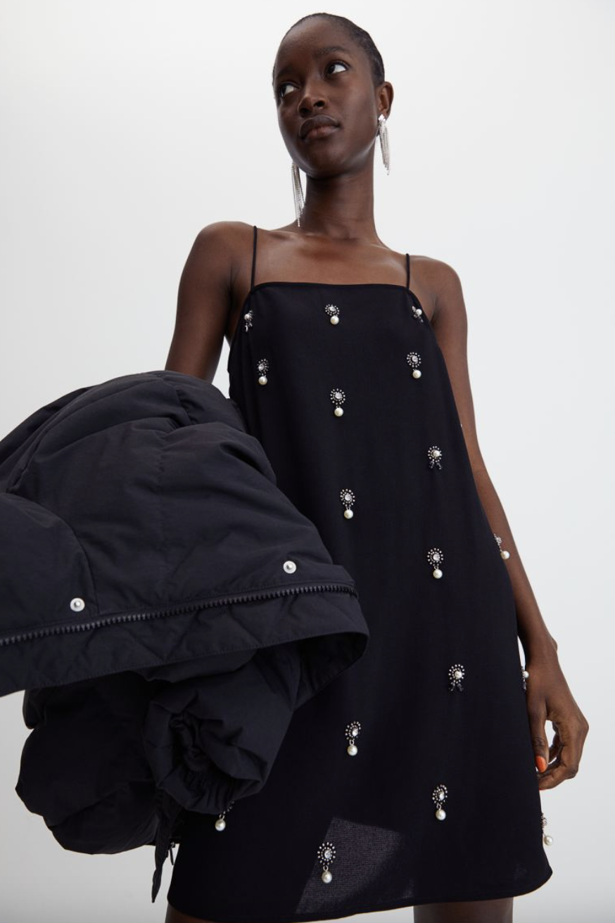 black female model with short hair wearing embellished black H&M+ Appliqu&#xe9;d Slip Dress (Photo via H&M)