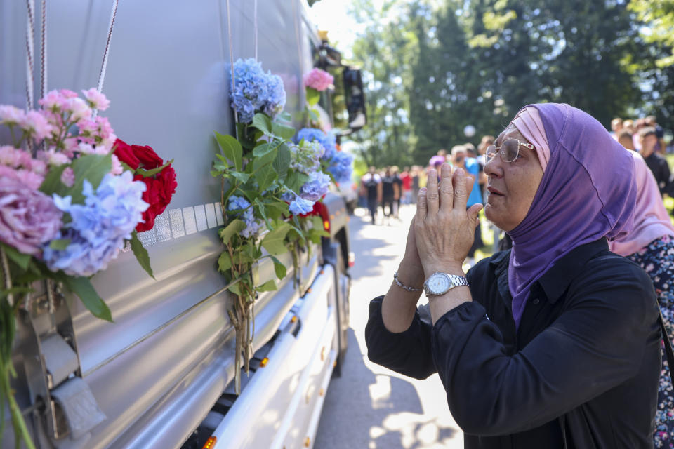 A Muslim women prays in Visoko, Bosnia, Sunday, July 9, 2023 next to a truck carrying 30 coffins with remains of the recently identified victims of the 1995 Srebrenica genocide. So far, the remains of more than 6,600 people have been found and buried at a vast and ever-expanding memorial cemetery in Potocari, outside Srebrenica. (AP Photo/Armin Durgut)