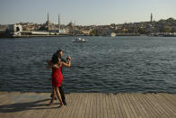 A couple dance by the Golden Horn leading to the Bosphorus Strait separating Europe and Asia, in Istanbul, Friday, May 14, 2021. Turkey is in the final days of a full coronavirus lockdown and the government has ordered people to stay home and businesses to close amid a huge surge in new daily infections. But millions of workers are exempt and so are foreign tourists. Turkey is courting international tourists during an economic downturn and needs the foreign currencies that tourism brings to help the economy as the Turkish lira continues to sink. (AP Photo/Emrah Gurel)