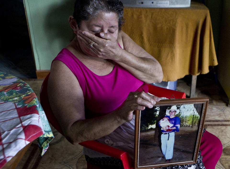 Maria Alvarenga, holding a photograph of her son Jose Salvador Alvarenga, put her hand over her mouth during an interview inside her home, in the village of Garita Palmera, El Salvador, Tuesday, Feb. 4, 2014. The account of her son's survival after more than 13 months in an open boat has proven a double miracle for his family, who lost touch with him years ago and thought he was dead. Jose Salvador Alvarenga said he left Mexico in December 2012 for a day of shark fishing and ended up on the remote Marshall Islands. (AP Photo/Esteban Felix)