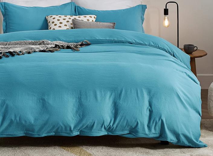 Teal bedding next a nightstand.