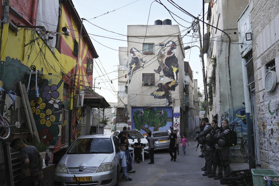 Israeli border police stand on a street lined with Palestinian homes painted in murals including one depicting goldfinches and an olive tree, that are part of the public art project 'I Witness Silwan' in the Silwan neighbourhood of east Jerusalem, Friday, Aug. 26, 2022. Palestinian and American artists have painted giant murals in an east Jerusalem district. The art project is meant to draw attention to the suffering of Palestinian residents of Silwan, a neighborhood near the Old City, who face Israeli arrests, home raids, demolitions, and the threat of evictions. (AP Photo/ Mahmoud Illean)