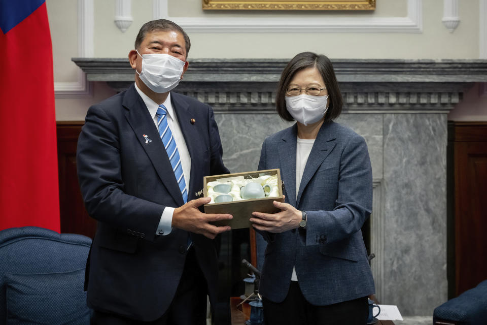 In this photo released by the Taiwan Presidential Office, Taiwan's President Tsai Ing-wen exchanges gifts with Japanese lawmaker and former Defense Minister Shigeru Ishiba during a meeting at the Presidential office in Taipei, Taiwan on Thursday, July 28, 2022. A group of Japanese lawmakers including two former defense ministers met with Taiwan's president on Thursday in a rare high-level visit to discuss regional security. (Taiwan Presidential Office via AP)