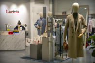 A clerk wearing a face mask uses her smartphone as she waits for customers in a clothing store at a shopping mall in Beijing, Wednesday, Jan. 29, 2020. Fears of a virus outbreak have kept many indoors and at home in China's capital. Cultural landmarks such as the Great Wall and Forbidden City have closed their doors to visitors, nearly deserted shopping malls have reduced their operating hours, and restaurants that remain open draw just a handful of customers. (AP Photo/Mark Schiefelbein)