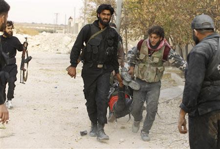 Free Syrian Army fighters carry the body of a fellow fighter who was killed by what the FSA said was during clashes with forces loyal to Syria's President Bashar al-Assad near Base 80 near Aleppo International airport, November 8, 2013. REUTERS/Molhem Barakat