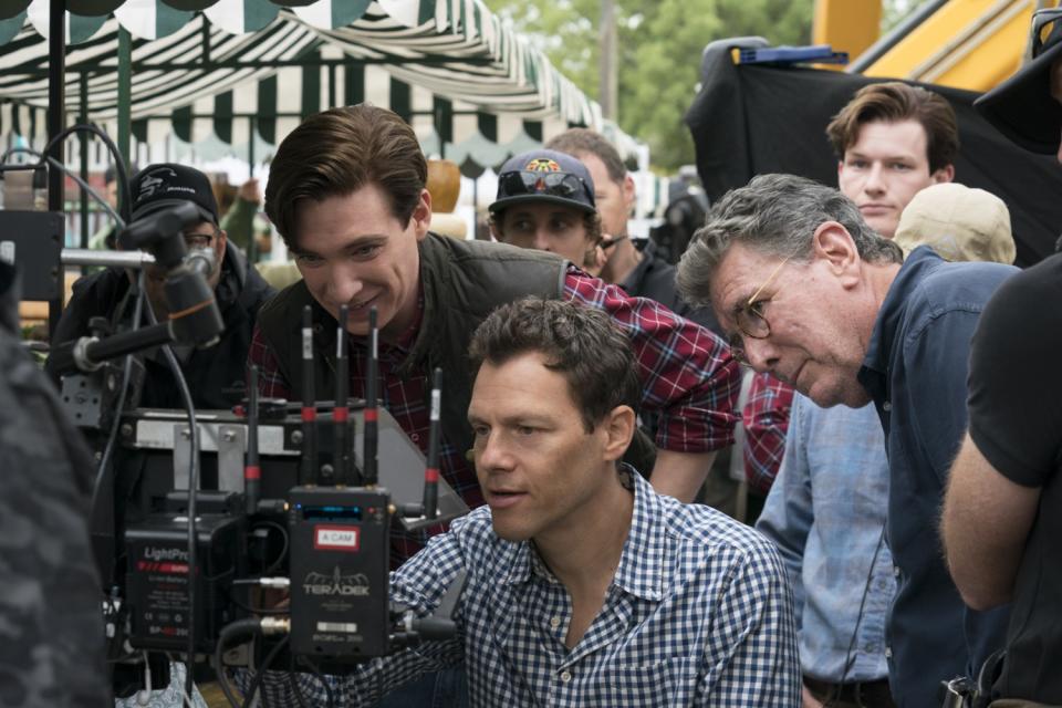 Three men huddle around equipment on the set of a movie